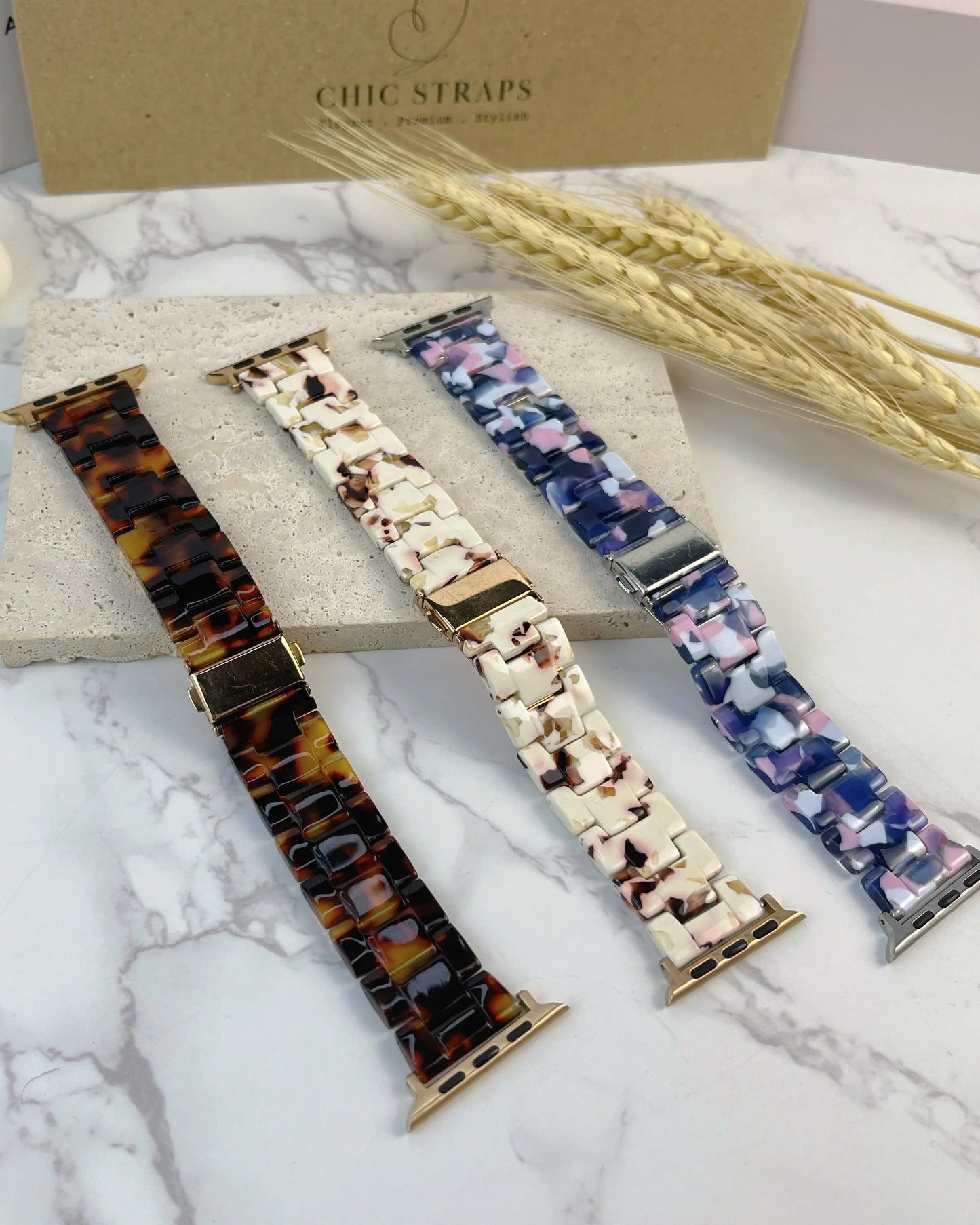 Three watch straps with different patterns on a marble surface with 'Chic Straps' branding.