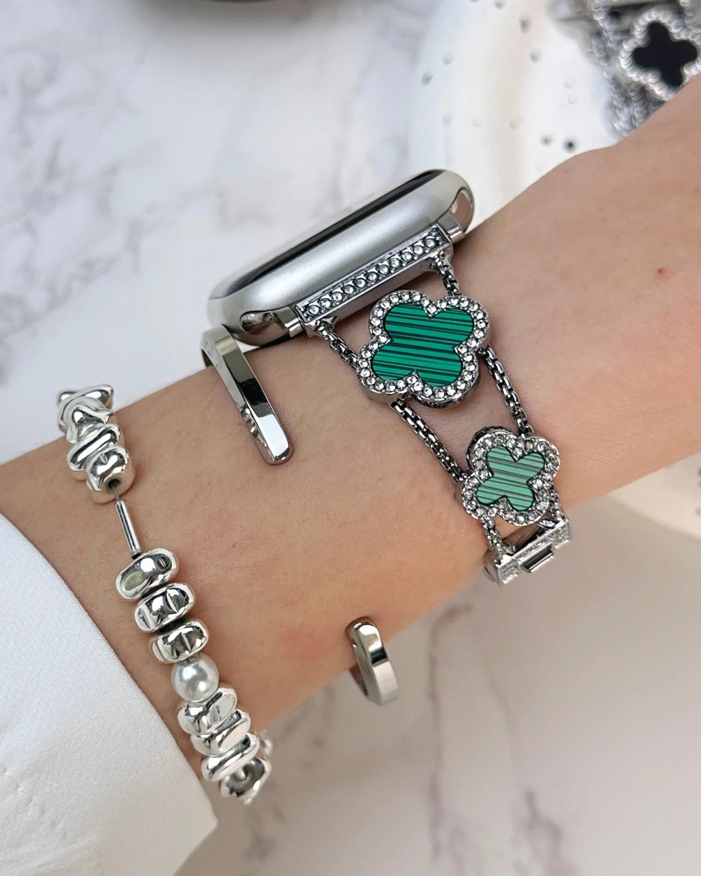 Close-up of a wrist wearing multiple bracelets on a marble surface