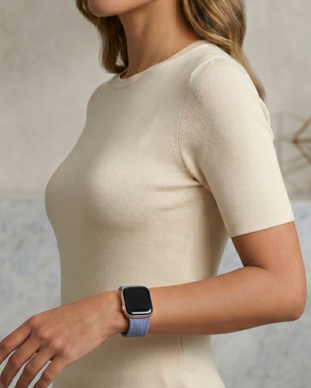 Woman wearing a beige dress and a smartwatch with a blue band.